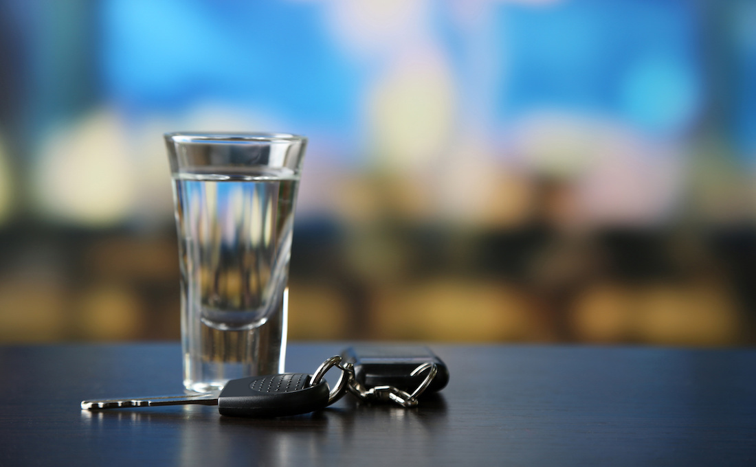 A glass of alcohol with car keys on a table